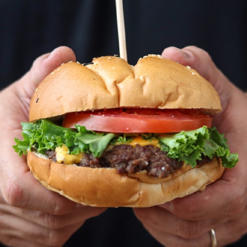 Hamburguesa A Dos Manos sostenida con las dos manos
